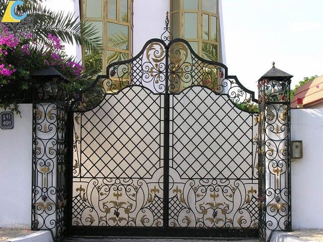 Mẫu cổng sắt uốn nghệ thuật có lắp thêm trụ và đèn được thiết kế che mờ phần cổng hiện đại và thời trang